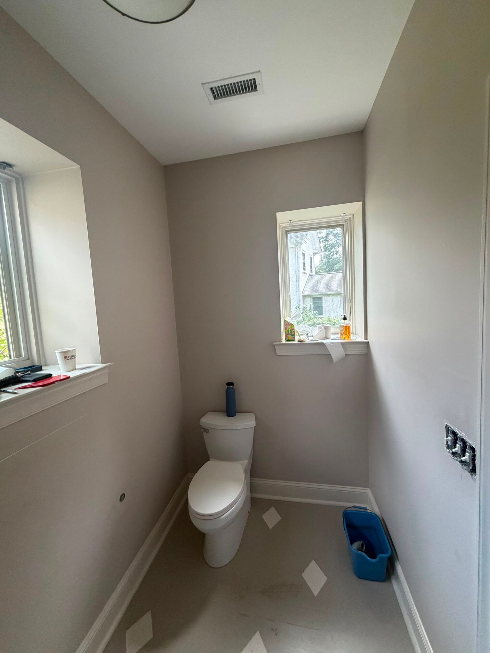 Same powder room before wallpaper, with plain greige painted walls