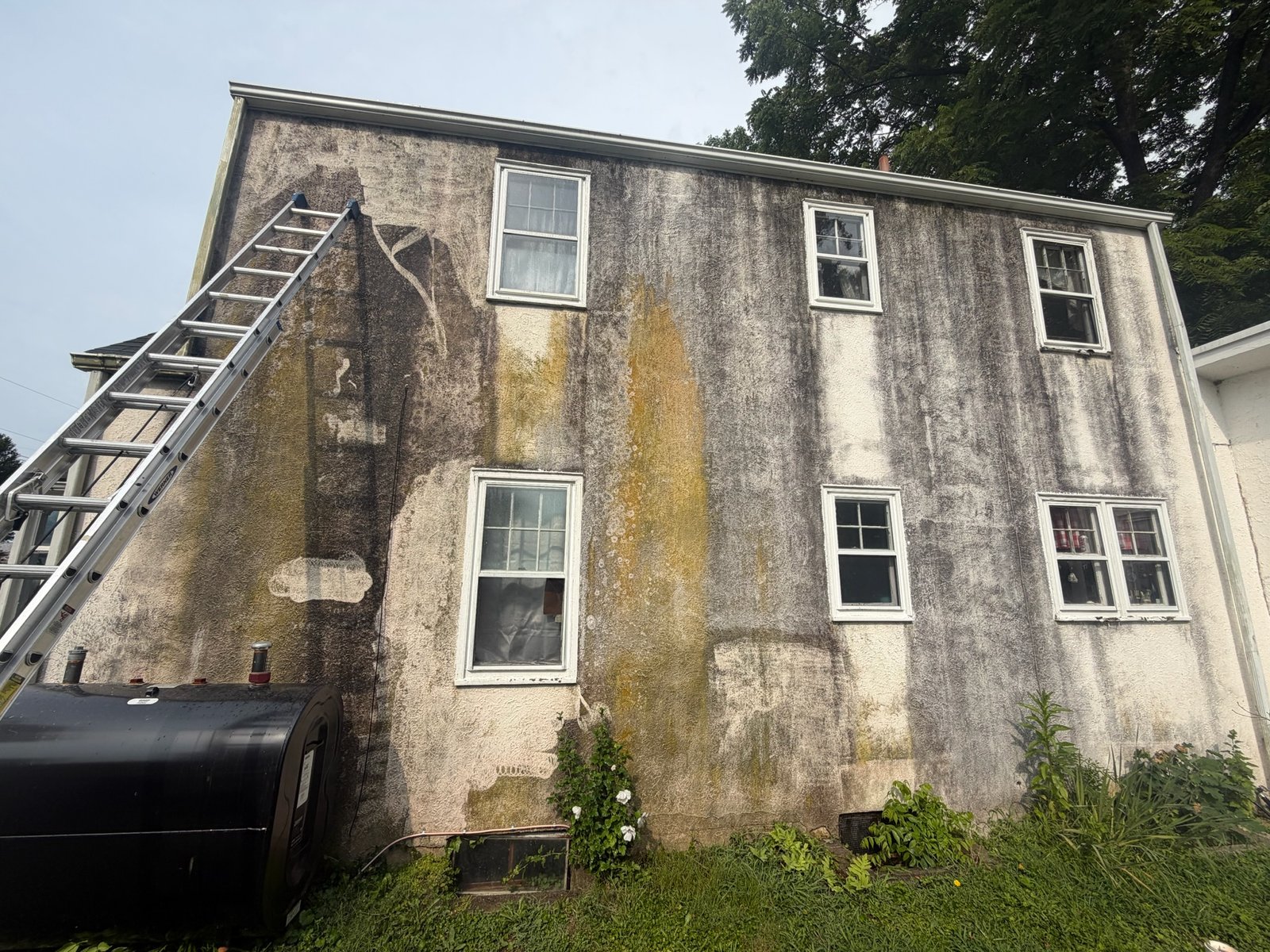 Home exterior covered with dirt, stains, and weather buildup before power washing